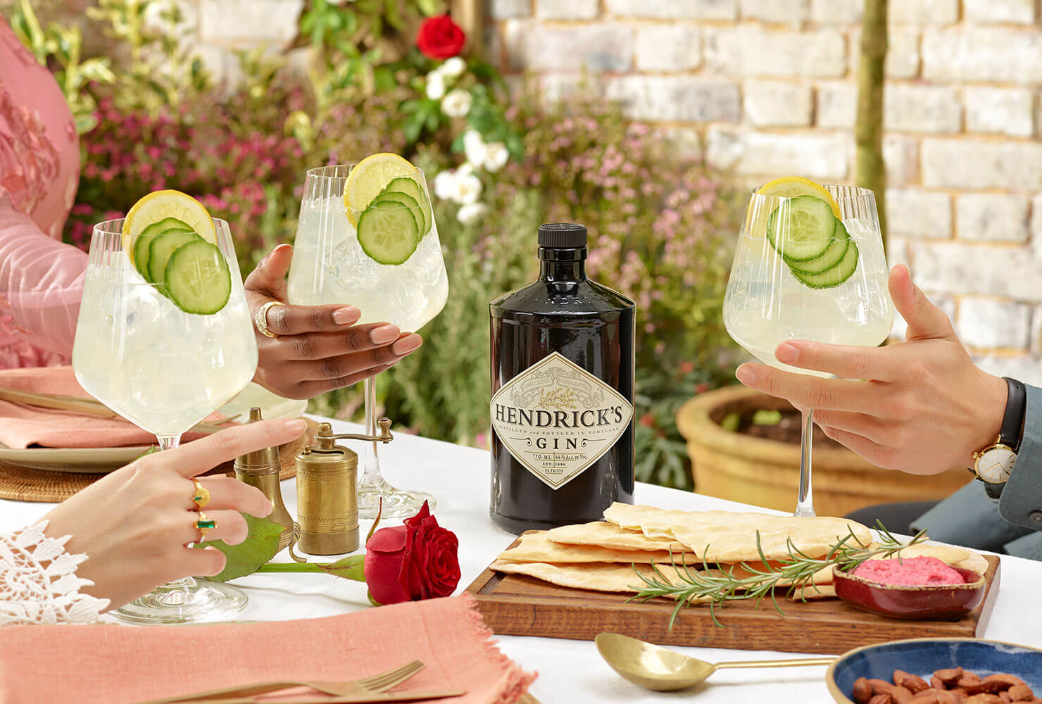 Hendrick's Gin Cucumber Lemonade cocktail people clinking glasses at a summer garden party